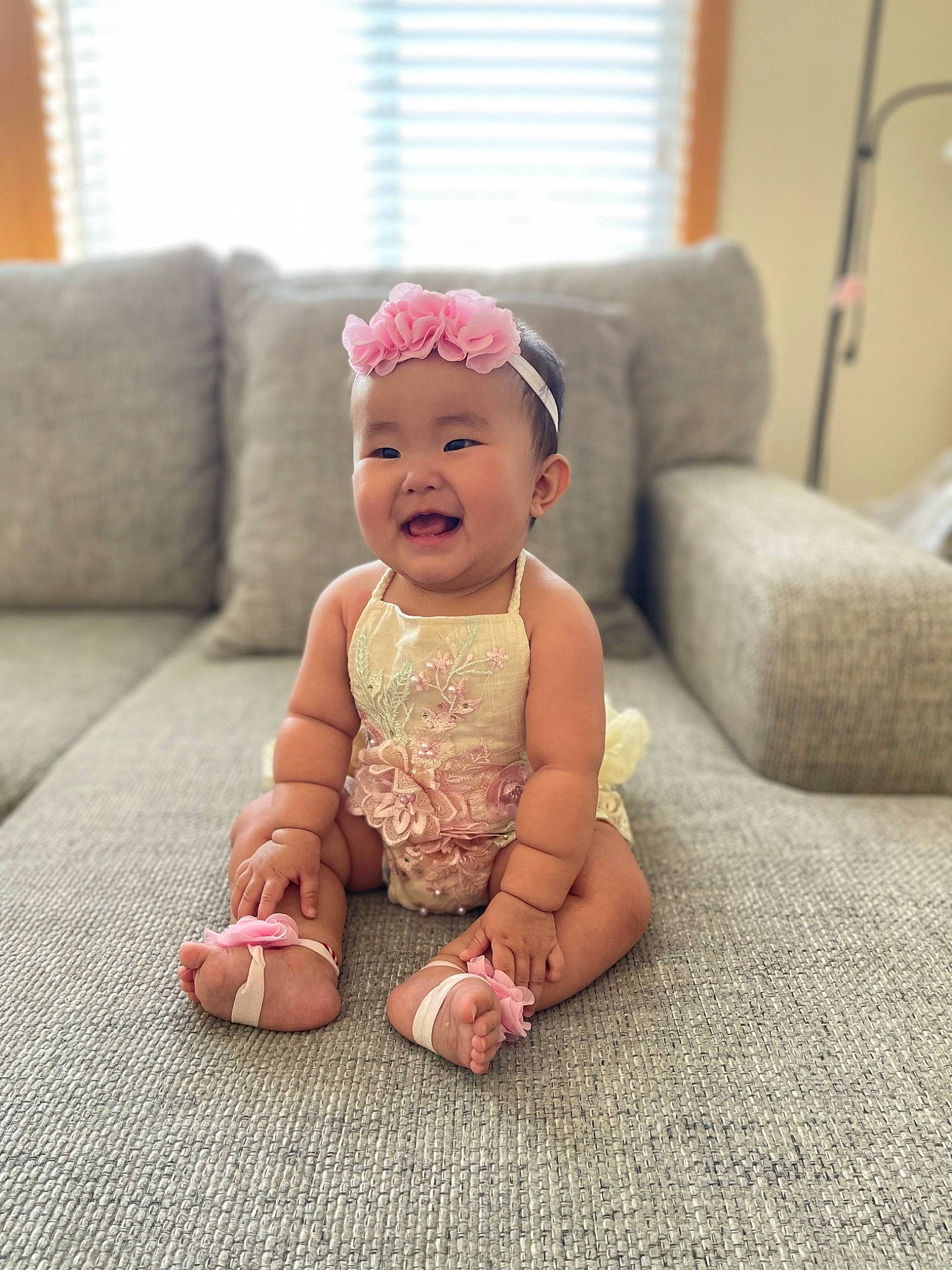 Seraphine is registered to the contest to win money with this photo: baby, baby_toddler_clothing, cap, comfort, couch, dress, eye, face, floor, flooring, foot, happy, hat, head, headwear, person, pink, skin, sleeve, smile