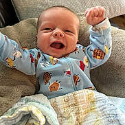 Liam joined the competition — help win amazing prizes! baby, infant, smiling, happy, blue_onesie, blanket, fist_raised, cozy, cute, face, indoors, soft_texture, patterned_clothing, child, newborn, person, expression, celebration, nap_time, comfort