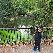 Dominic joined the competition — help win amazing prizes! child, boy, outdoor, nature, pond, trees, greenery, railings, path, leaves, fall, water, reflection, casual_clothing, sneakers, curious, standing, daylight, forest, scenery