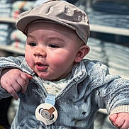 Sohan participe au concours pour gagner de l'argent avec cette photo : baby, blurred_background, cap, chubby_cheeks, close_up, clothing_store, cute, hand, hat, indoor, infant, jacket, pacifier, plush_jacket, portrait, sitting, skin, smiling, store_shelves, toddler