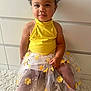 Tiyana participe au concours pour gagner de l'argent avec cette photo : barefoot, carpet, child, curly_hair, cute, fashion, flower_skirt, happy, indoor, person, playful, portrait, room, sitting, skin, smiling, soft_lighting, toddler, yellow_top, young_child