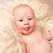 Delta-Mae is registered to the contest to win money with this photo: baby, infant, tongue_out, blue_eyes, curly_blanket, soft_texture, skin, cheeks, portrait, naked_torso, cute, expression, child, newborn, fluffy, warm, lying_down, innocence, closeup, adorable