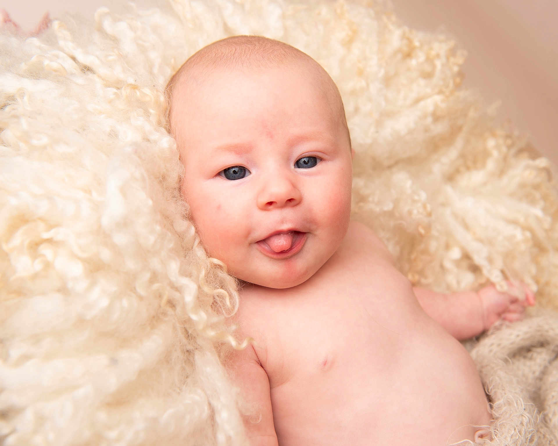 Delta-Mae is registered to the contest to win money with this photo: baby, infant, tongue_out, blue_eyes, curly_blanket, soft_texture, skin, cheeks, portrait, naked_torso, cute, expression, child, newborn, fluffy, warm, lying_down, innocence, closeup, adorable