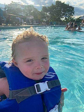 Chase is registered to the contest to win money with this photo: azure, body_of_water, cool, electric_blue, face, fun, happy, lake, leisure, mammal, mountain, person, personal_protective_equipment, recreation, sky, summer, toddler, travel, tree, vertebrate