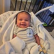 Brent joined the competition — help win amazing prizes! baby, smiling, blanket, onesie, striped_clothing, bear_design, infant, cozy, indoor, baby_gate, wooden_floor, cute, child, person, portrait, happy, wrapped, soft, home, comfort