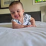 baby, smiling, tongue_out, bed, onesie, infant, happy, indoor, child, person, head, face, furniture, painting, stained_glass, wall, room, crawling, cute, expression