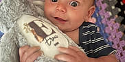 Ernie is registered to the contest to win money with this photo: baby, child, stuffed_animal, plush_toy, crocheted_blanket, colorful, blue_striped_clothing, happy, smiling, face, hands, indoor, closeup, cute, infant, soft_toy, texture, pattern, comfort, young