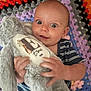 baby, child, stuffed_animal, plush_toy, crocheted_blanket, colorful, blue_striped_clothing, happy, smiling, face, hands, indoor, closeup, cute, infant, soft_toy, texture, pattern, comfort, young