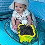 baby, child, hat, yellow_basket, sand, tent, blue_tent, seat, infant, play, outdoor, foot, hand, striped_hat, white_seat, curious, smile, toy, plastic_basket, casual_clothing