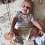 baby, child, smiling, play_mat, onesie, socks, cute, infant, happy, tongue_out, indoor, floor, clothing, person, lying_down, baby_girl_or_boy, playful, head, face, skin
