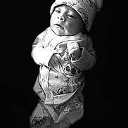 Noah is registered to the contest to win money with this photo: baby, infant, black_and_white, portrait, hat, clothing, pajamas, cute, young_child, face, hands, expression, dark_background, studio, newborn, soft_light, sleepwear, animal_print, headwear, isolated