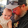 baby, man, beard, cap, glasses, flower_filter, indoor, kitchen, furniture, holding, child, cute, portrait, affection, casual_clothing, skin, arm, person, love, family