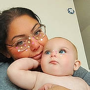 Ensleigh is registered to the contest to win money with this photo: woman, baby, face, glasses, skin, hand, indoor, person, closeup, digital_stickers, flower_stickers, baby_boy, affection, casual_clothing, portrait, head_and_shoulders, holding, smoke_detector, neutral_wall, family