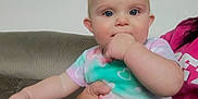 Ensleigh is registered to the contest to win money with this photo: baby, child, infant, person, hand, face, couch, clothing, colorful, sitting, indoor, adult_hand, pink, pattern, heart, cute, cheeks, eyes, comfort, casual