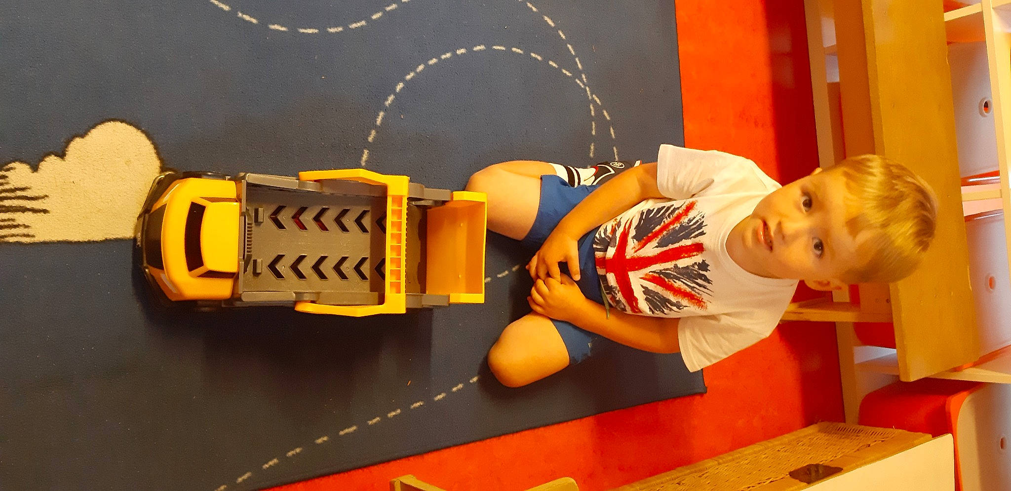 Evan participe au concours pour gagner de l'argent avec cette photo : animation, automotive_wheel_system, child, construction_equipment, fashion_accessory, flooring, fun, machine, orange, person, play, recreation, room, t_shirt, table, toddler, toy, toy_vehicle, wood