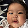 Jillian joined the competition — help win amazing prizes! baby, infant, face, closeup, curious, hand, skin, dark_hair, blanket, pattern, white_clothing, pink_dots, laying_down, indoors, portrait, cute, child, young, expression, soft_lighting
