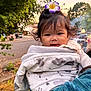 Jillian joined the competition — help win amazing prizes! baby, child, blanket, flower, smile, outdoor, person, portrait, cute, holding, face, young_child, hair, nature, sunset, tree, clothing, cozy, happy, park