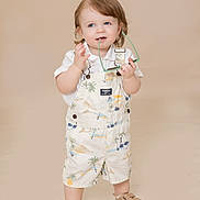 Archer is registered to the contest to win money with this photo: toddler, child, standing, sunglasses, overalls, white_shirt, beige_background, shoes, cute, playful, innocent, portrait, studio, fashion, young_child, smiling, short_hair, indoors, casual_clothing, person