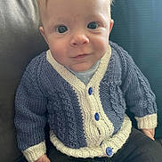 Brendon is registered to the contest to win money with this photo: baby, child, face, knitwear, cardigan, blue, white, buttons, couch, cushion, clothing, sitting, portrait, indoor, person, smile, young, cute, cozy, casual