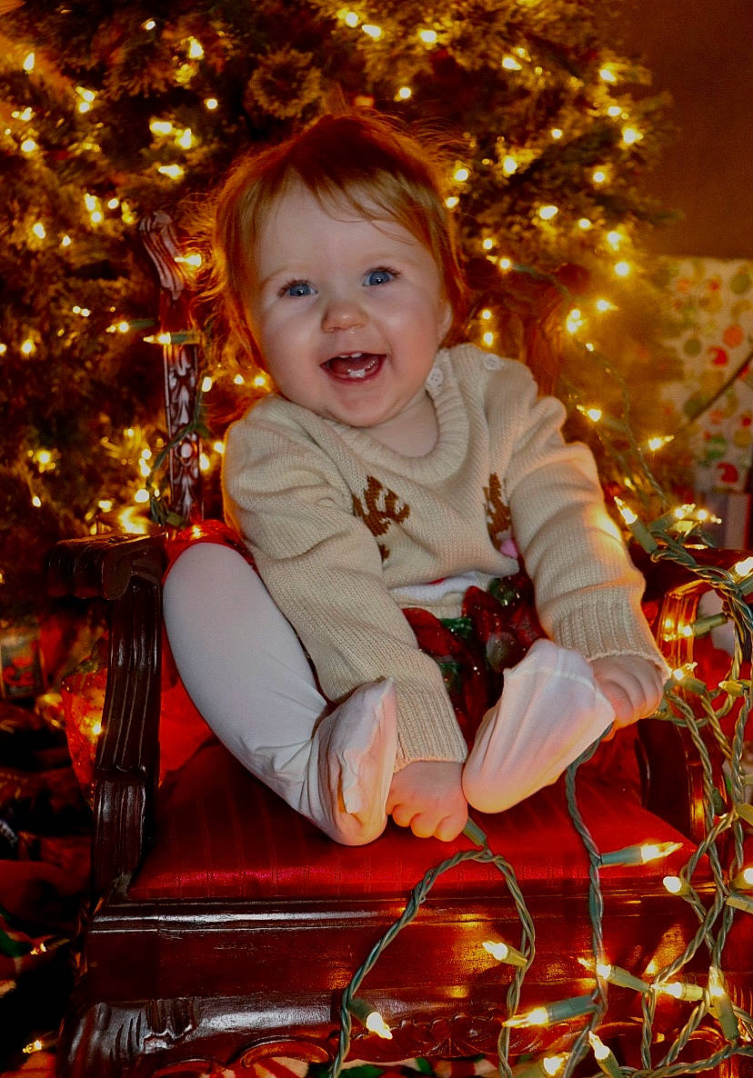 Avalee joined the competition — help win amazing prizes! baby_toddler_clothing, cheek, child, christmas, christmas_decoration, christmas_ornament, christmas_tree, event, facial_expression, fun, happy, head, holiday, holiday_ornament, light, ornament, person, sitting, smile, standing