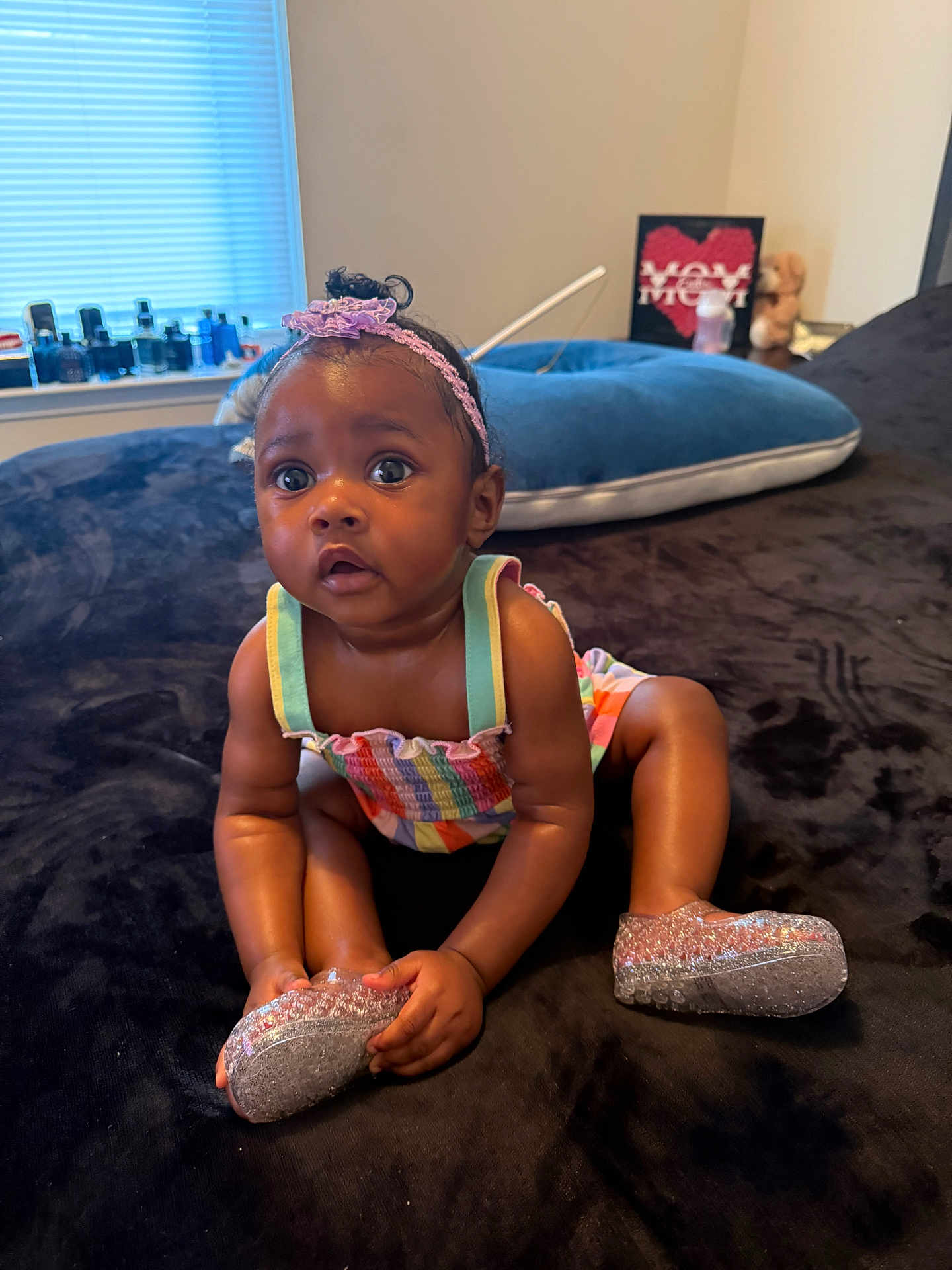 Endia is registered to the contest to win money with this photo: baby, child, infant, sitting, colorful_clothing, sparkly_shoes, headband, curly_hair, indoors, window, cushion, plush_surface, wide_eyes, cute, person, young_child, black_baby, expression, room, soft_lighting