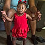 toddler, child, adult, red_outfit, sparkly_shoes, hair_bows, carpet, couch, living_room, person, holding_hands, smiling, indoor, furniture, legs, seated, cute, family, support, home