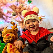 Archie joined the competition — help win amazing prizes! baby, child, smiling, hat, pom_poms, red_clothing, plush_toy, reindeer, christmas_tree, holiday, festive, indoor, decorations, cute, happy, portrait, soft_toys, christmas, seasonal, celebration