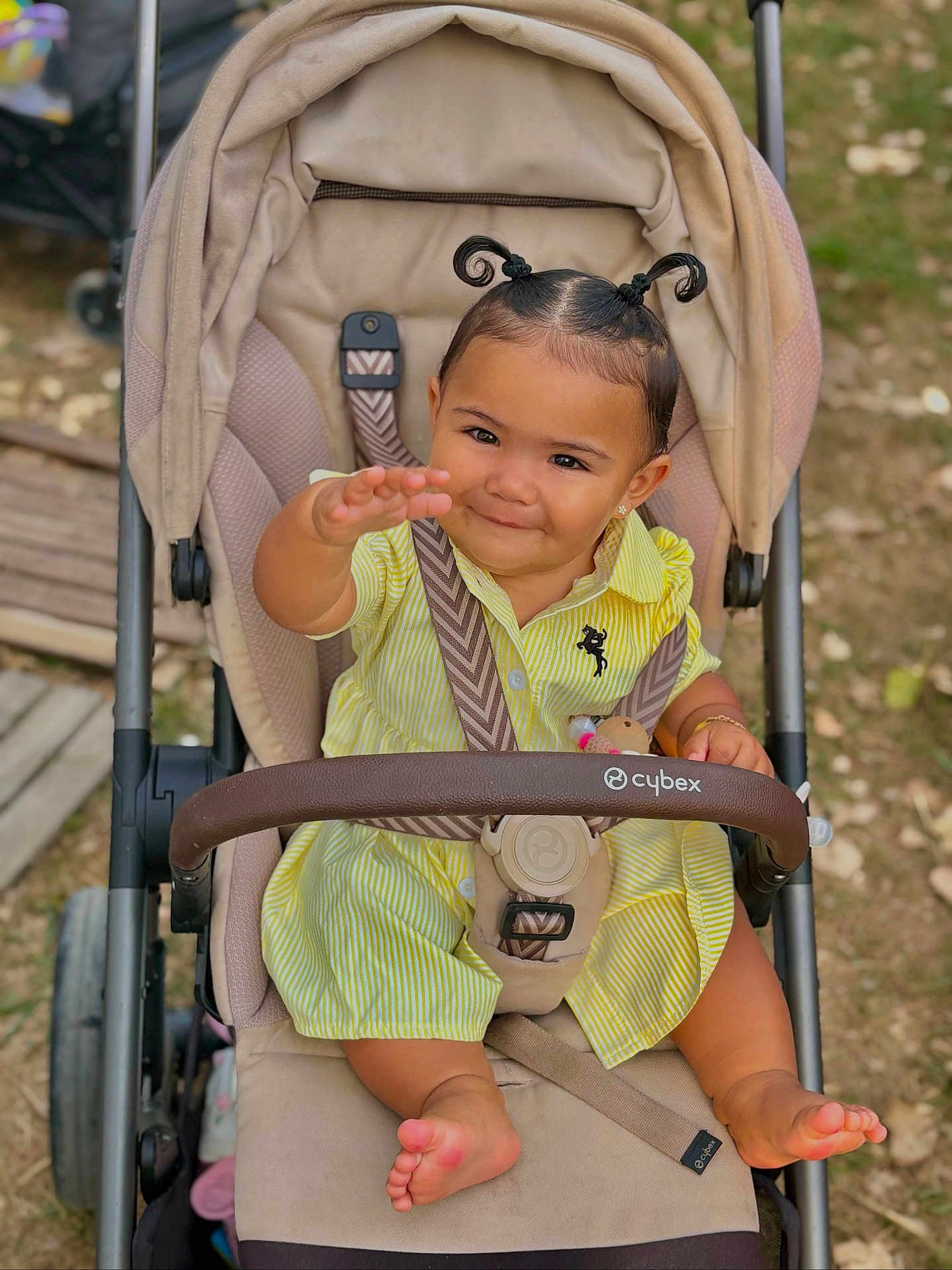 Méeva participe au concours pour gagner de l'argent avec cette photo : toddler, child, stroller, yellow_dress, smiling, outdoor, baby, seat_belt, hair_pigtails, barefoot, cute, person, infant, sitting, playful, happy, baby_clothes, park, daylight, cute_expression
