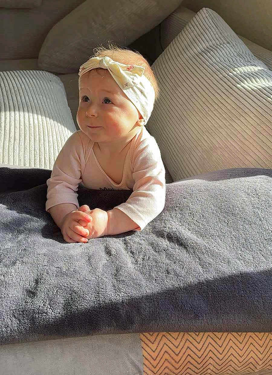 Blum Lydia participe au concours pour gagner de l'argent avec cette photo : baby, child, headband, blanket, couch, curious, expression, face, hands, indoors, light, looking_up, pink_clothing, plush, portrait, rosy_cheeks, sitting, soft_light, toddler, young_child