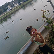 Melyne Marie participe au concours pour gagner de l'argent avec cette photo : child, girl, sunglasses, river, water, ducks, guardrail, plants, grass, buildings, cars, outdoor, nature, casual_clothing, playful, summer, footwear, curly_hair, urban, daytime