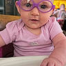 Penelope joined the competition — help win amazing prizes! baby, glasses, purple_glasses, pink_shirt, dinosaur_print, infant, child, face, hand, curious_expression, highchair, indoor, blurred_background, person, closeup, young_child, skin, sitting, feeding, cute