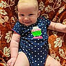 baby, infant, smile, polka_dot, onesie, cupcake_design, blanket, patterned_blanket, cozy, cute, child, happy, portrait, skin, arm, leg, indoors, natural_light, person, young_child