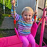 child, toddler, swing, pink_swing, outdoor, playground, hoodie, colorful_clothing, smiling, happy, blue_eyes, rope, grass, house, sunlight, backyard, play, toy, person, daylight