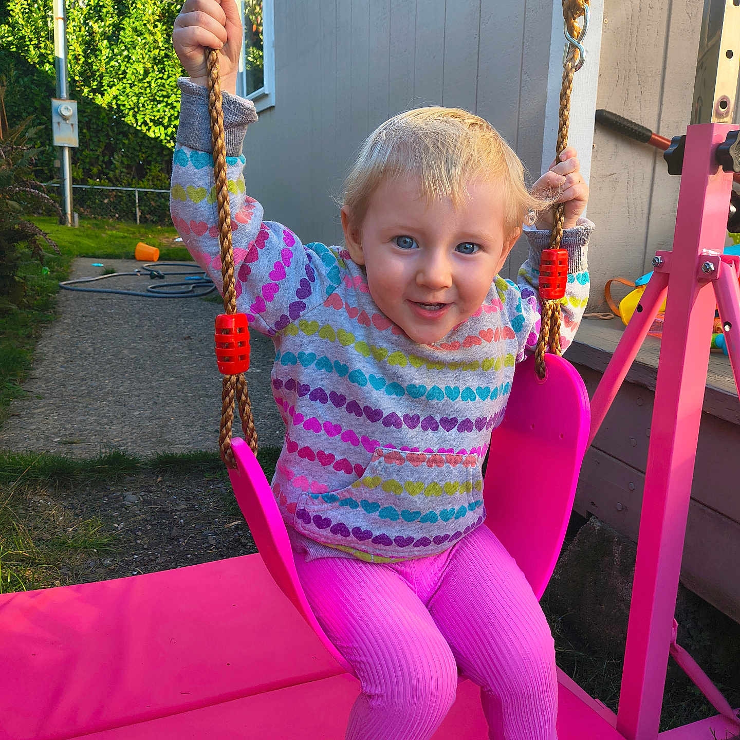 Vanessa is registered to the contest to win money with this photo: child, toddler, swing, pink_swing, outdoor, playground, hoodie, colorful_clothing, smiling, happy, blue_eyes, rope, grass, house, sunlight, backyard, play, toy, person, daylight