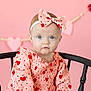 baby, infant, headband, bow, pink_background, heart_pattern, dress, wooden_chair, chair, blue_eyes, portrait, sitting, cute, adorable, studio_photo, valentine_theme, garland, decor, close_up, fashion