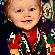 Justin joined the competition — help win amazing prizes! child, baby, toddler, smiling, portrait, blue_eyes, blonde_hair, colorful_jacket, sport_logo, tooth, festive_background, snowman_pattern, studio_photo, carpet, close_up, happy, cheeks, crawling_pose, holiday_theme, young