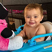 Margaret is registered to the contest to win money with this photo: baby, smile, walker, toy, plush_toy, indoor, child, happy, face, person, playpen, blue, pink, cute, sitting, infant, furniture, home, young_child, expression