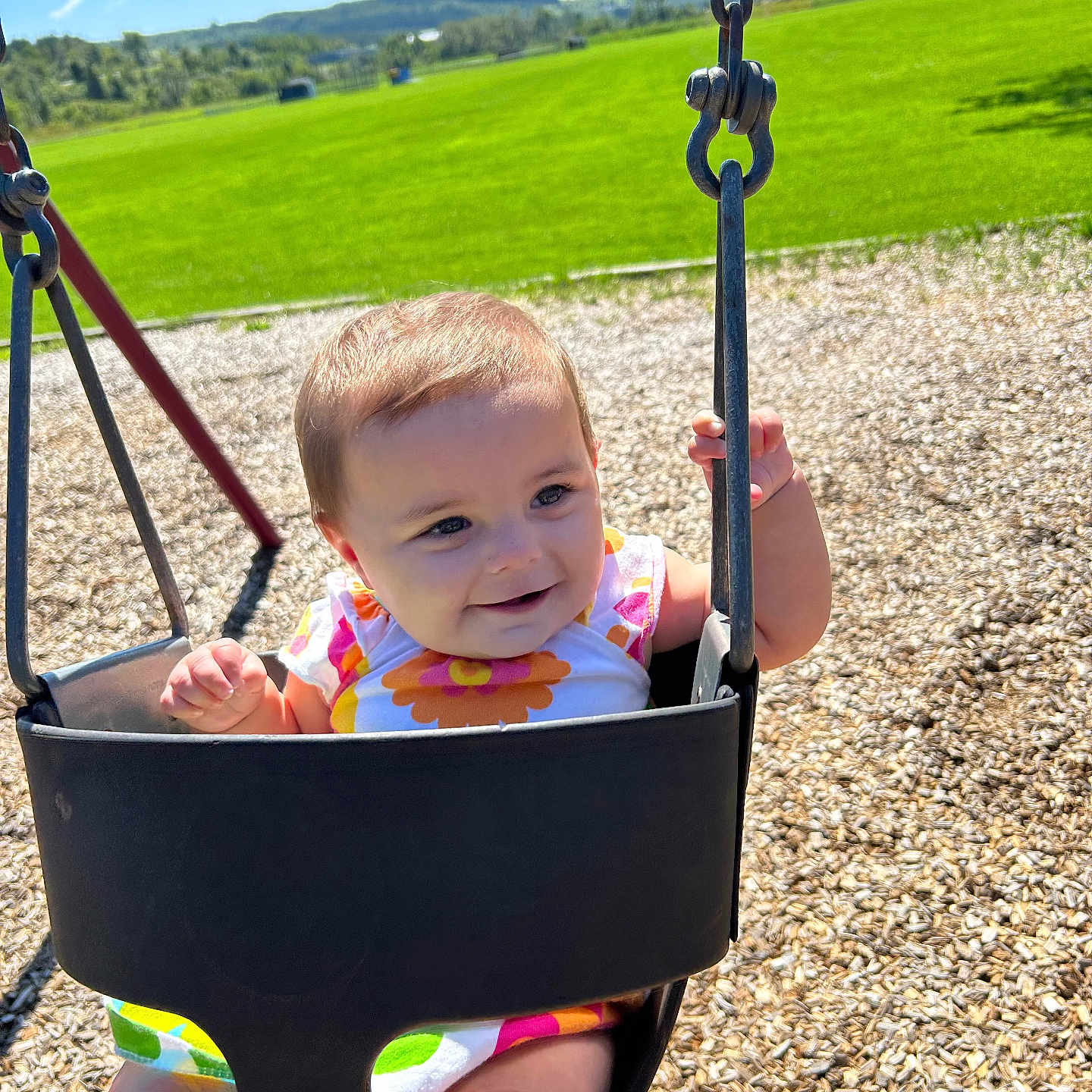 Margaret is registered to the contest to win money with this photo: baby, swing, playground, child, outdoor, sunny, grass, woodchips, smile, happy, summer, daylight, park, nature, person, seat, metal_chain, clothing, face, fun