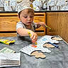 Eloy is registered to the contest to win money with this photo: child, toddler, crown, coloring, crayons, craft, table, restaurant, fast_food, birthday, creative, focused, seated, wood_paneling, paper, cardboard, drawing, indoor, portrait, family_activity