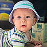 baby, blue, candid, casual_clothing, child, curious, drool, face, green, hands, hat, indoor, infant, lying_down, portrait, soft_light, striped_clothing, toddler, white, young_child