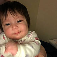 Isabela joined the competition — help win amazing prizes! baby, child, closeup, clothing, cozy, cute, dark_hair, face, hand, holding, human, indoor, infant, ladybug_print, person, portrait, sleepsuit, smile, warm_lighting, young