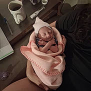 Savanna is registered to the contest to win money with this photo: newborn, baby, sleeping, infant, blanket, pink_blanket, swaddled, portrait, face, indoors, lap, adult, caregiver, bedside_table, coffee, thermometer, tissues, pacifier, home, peaceful