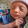 Savanna is registered to the contest to win money with this photo: newborn, baby, sleeping, portrait, close_up, face, infant, hat, striped_hat, blue_clothing, blanket, swaddled, hand, fingers, indoors, bed, peaceful, cute, resting, photography