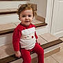 child, cozy, curly_hair, cute, festive, happy, holiday, home, indoor, person, portrait, red_clothing, santa_outfit, sitting, smile, stairs, tile_floor, toddler, wooden_stairs, young_child