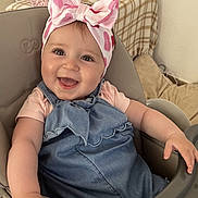 Magda a rejoint le concours — aidez-le/la à gagner de superbes lots ! baby, child, smiling, happy, headband, bow, denim_dress, high_chair, indoor, cute, toddler, person, face, skin, arm, furniture, seat, clothing, infant, portrait