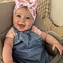 baby, child, smiling, happy, headband, bow, denim_dress, high_chair, indoor, cute, toddler, person, face, skin, arm, furniture, seat, clothing, infant, portrait