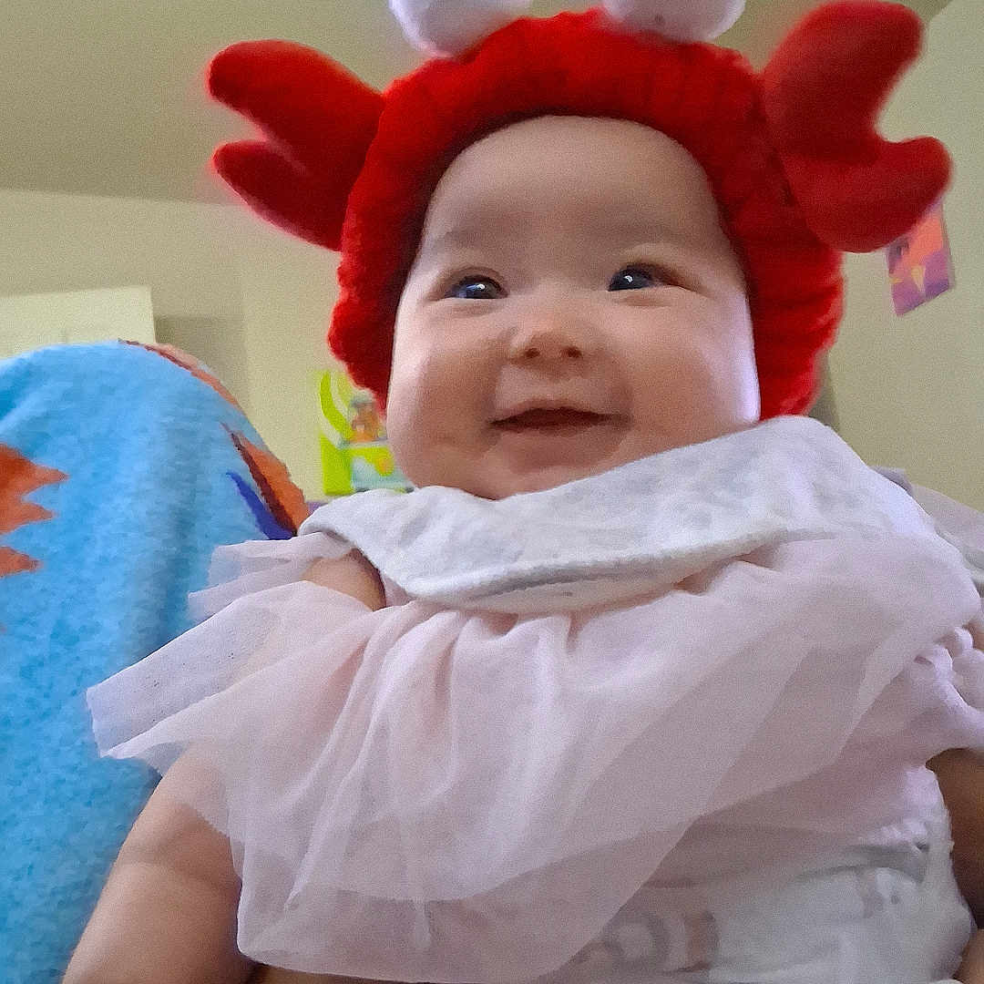 Nahanni joined the competition — help win amazing prizes! baby, blanket, child, crab_hat, cute, diaper, eyes, face, hand, happy, home, indoors, infant, legs, pink_clothing, portrait, red_hat, seated, smiling, soft_toys