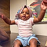 Jaya is registered to the contest to win money with this photo: arms_raised, artwork, baby, child, cute, dark_skin, denim_shorts, fashion, furniture, happy, home, indoor, infant, photography, pink_hat, pink_shirt, portrait, sitting, smiling, table