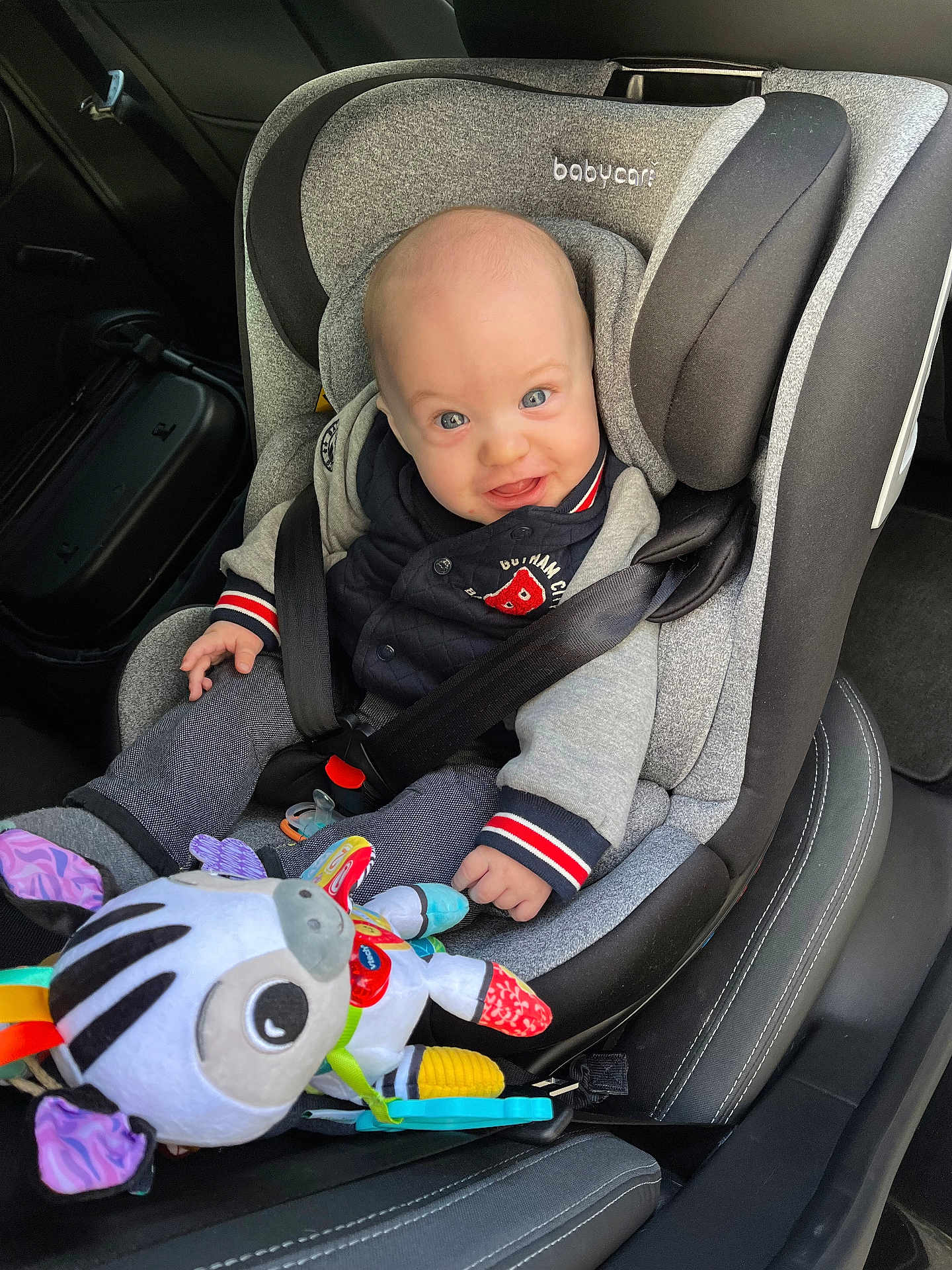 Timéo a rejoint le concours — aidez-le/la à gagner de superbes lots ! baby, car_seat, child, smiling, toy, plush_toy, zebra, seatbelt, car_interior, clothing, jacket, pants, hand, head, face, sitting, infant, safety, colorful, happy