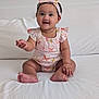 baby, child, smiling, sitting, headband, romper, butterfly_pattern, indoor, bed, white_bedspread, cute, happy, person, infant, young_child, clothing, skin, hand, foot, portrait